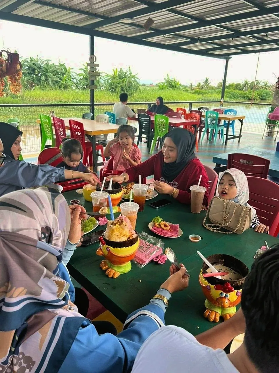 Keluarga menikmati hidangan di meja tepi Sungai Derga